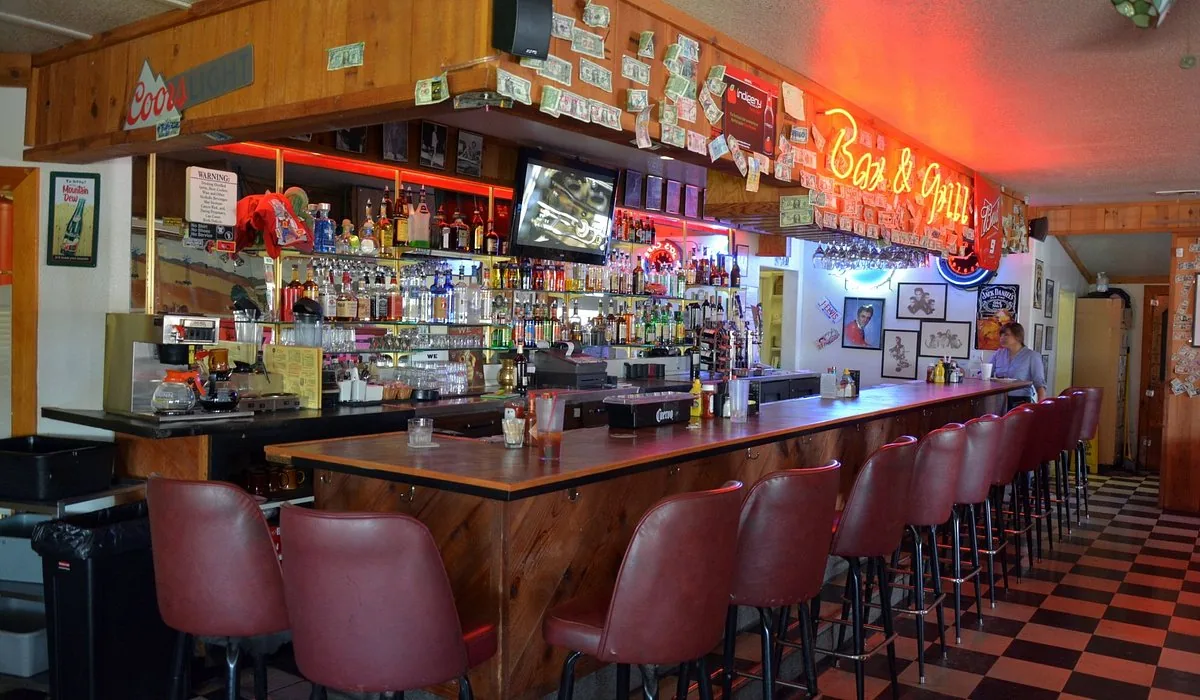 The full bar at 50's Roadhouse, lined with liquor bottles under neon Bar & Grill signage and 1950s memorabilia